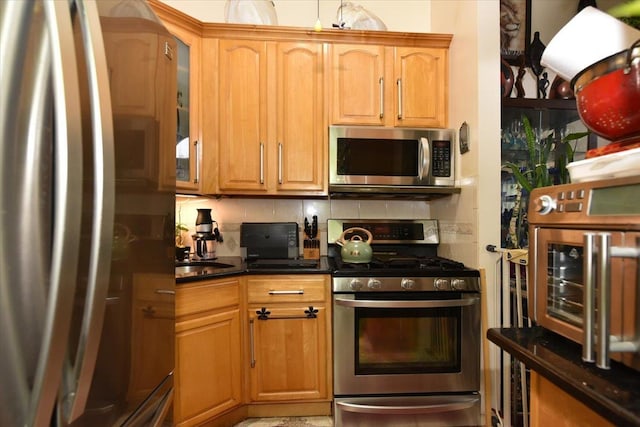 kitchen featuring dark stone counters, decorative backsplash, and stainless steel appliances