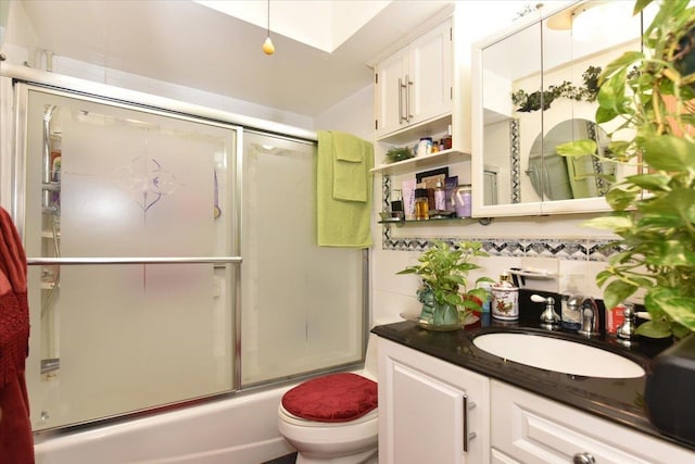 full bathroom featuring decorative backsplash, toilet, combined bath / shower with glass door, and vanity