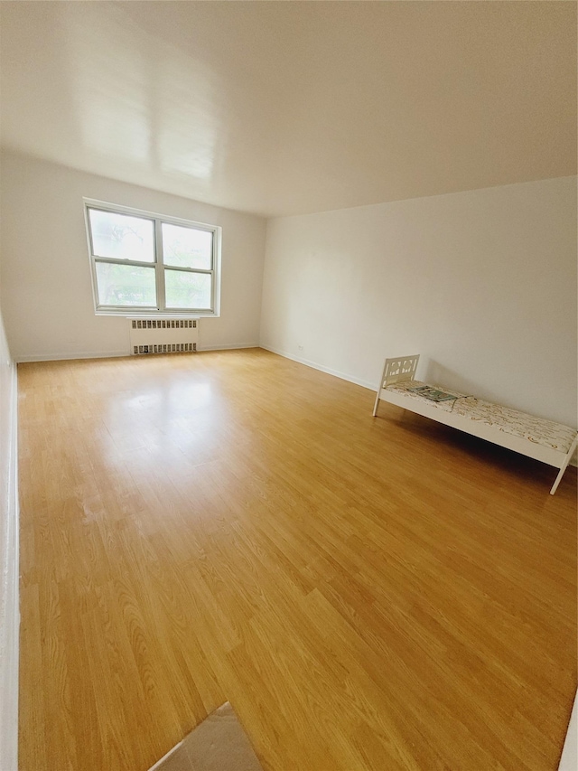 unfurnished room with radiator heating unit and light wood-type flooring