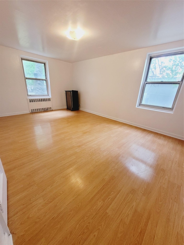 unfurnished room featuring light wood-type flooring and radiator