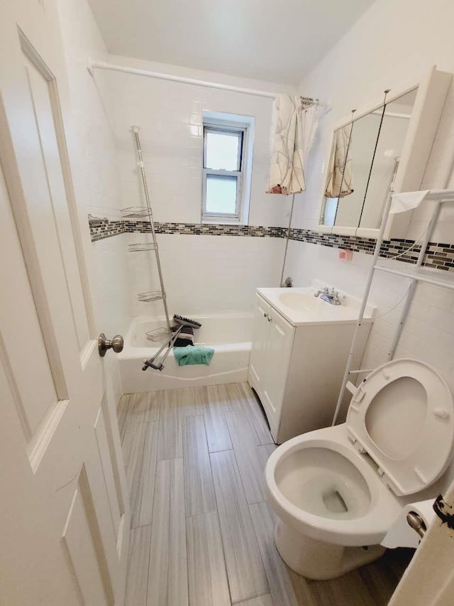 full bathroom featuring vanity, wood-type flooring, tile walls, toilet, and tiled shower / bath