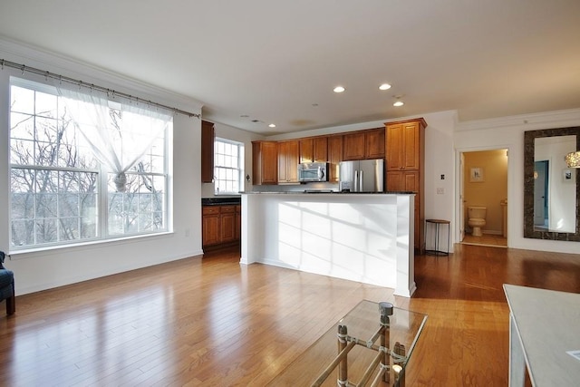 kitchen with ornamental molding, appliances with stainless steel finishes, and light hardwood / wood-style flooring