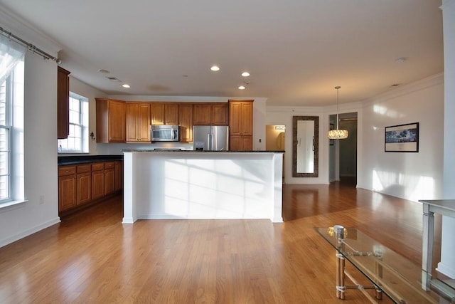 kitchen featuring crown molding, pendant lighting, stainless steel appliances, and light hardwood / wood-style floors