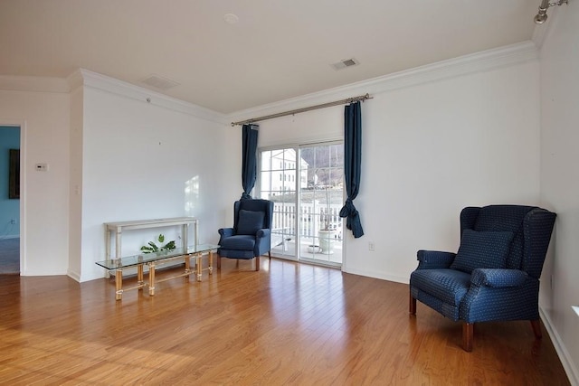 living area with crown molding and wood-type flooring