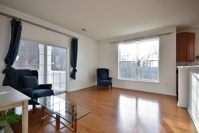 living area with light hardwood / wood-style floors, crown molding, and a wealth of natural light