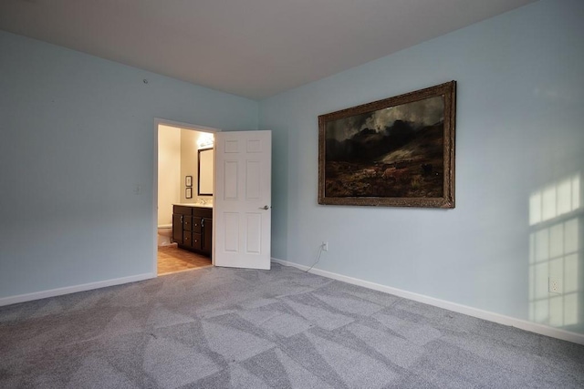 unfurnished bedroom with ensuite bathroom and light colored carpet