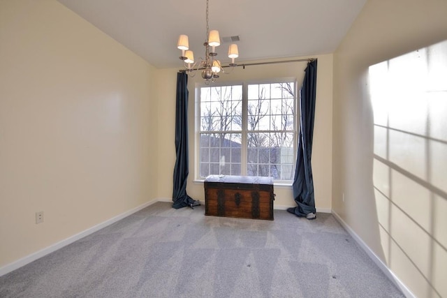 empty room featuring light carpet, a chandelier, and vaulted ceiling