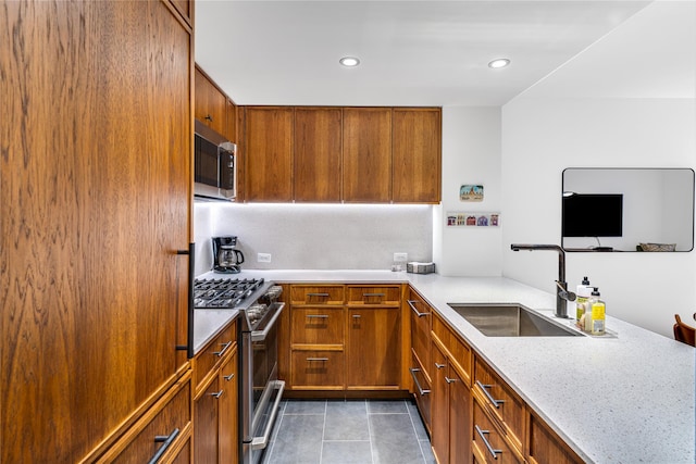 kitchen with stainless steel appliances, sink, light tile patterned floors, and light stone counters