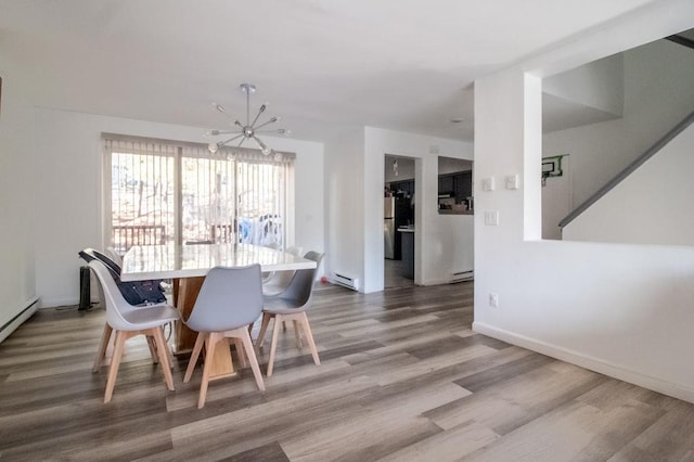 dining area with an inviting chandelier, wood-type flooring, and baseboard heating