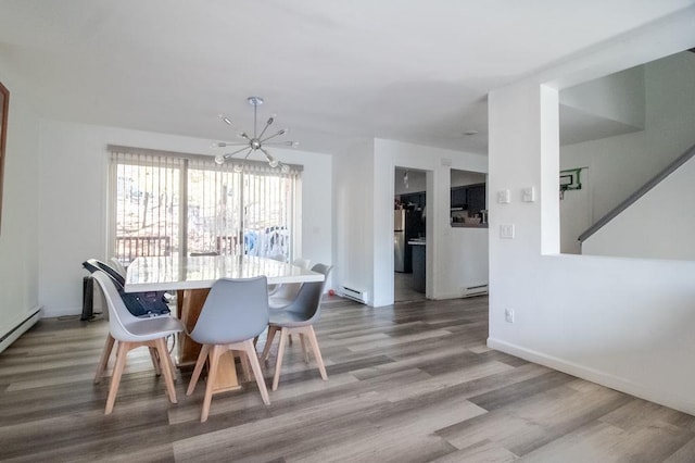 dining area with a baseboard radiator, hardwood / wood-style floors, and an inviting chandelier