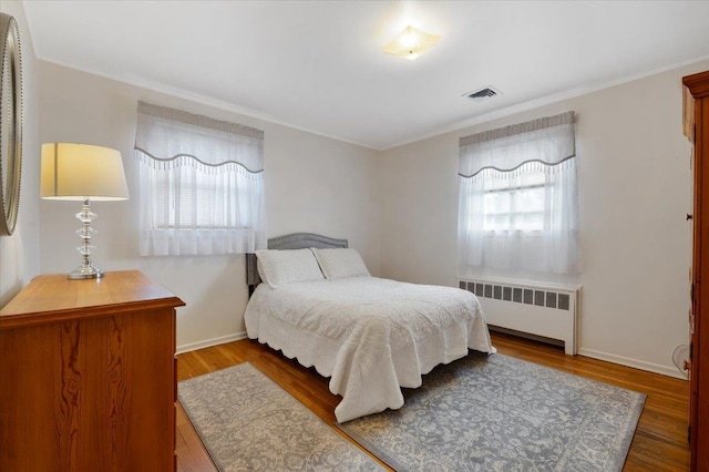 bedroom featuring ornamental molding, dark wood-type flooring, and radiator