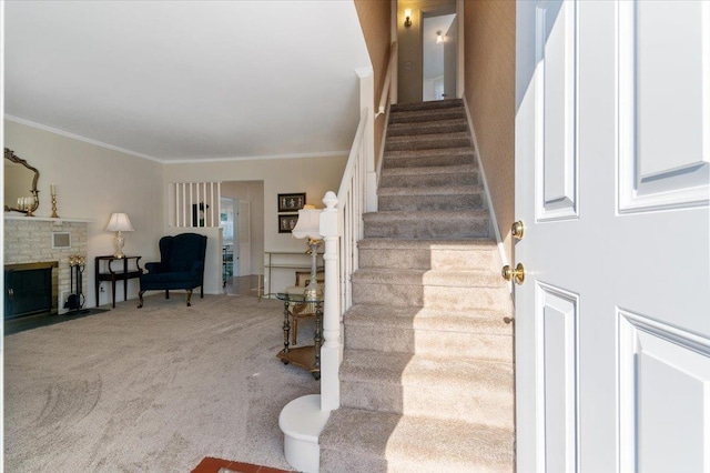 stairway with carpet flooring, a stone fireplace, and ornamental molding