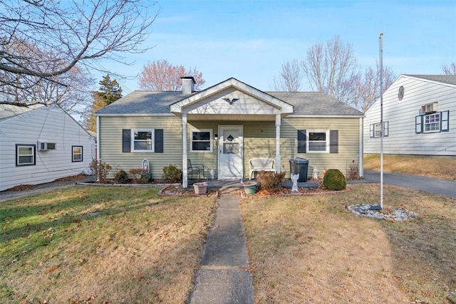 view of front of property with a front lawn and a wall mounted AC