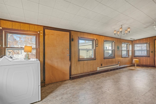 interior space featuring washing machine and dryer, wooden walls, a baseboard heating unit, and a chandelier