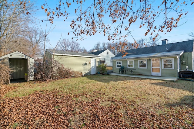 rear view of house with a patio area, a yard, and a storage shed