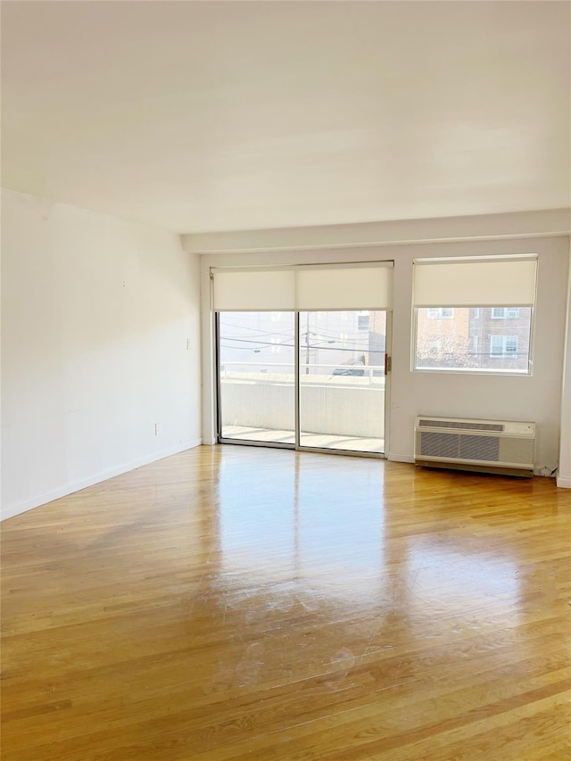 spare room with light wood-type flooring and a wall mounted AC