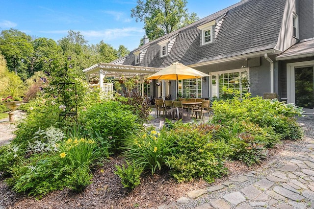 rear view of property featuring a pergola and a patio area