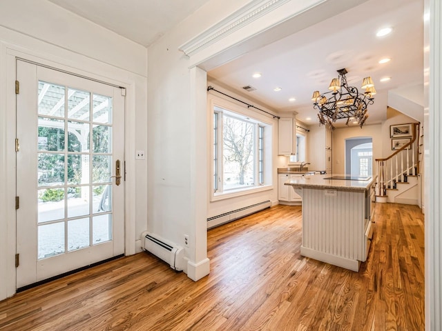 kitchen featuring baseboard heating, decorative light fixtures, light hardwood / wood-style floors, and white cabinets