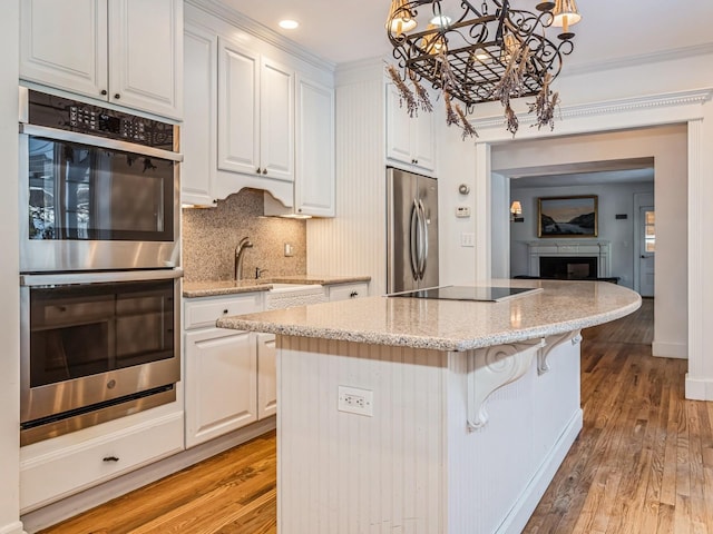 kitchen featuring stainless steel appliances, a center island, white cabinets, and decorative light fixtures