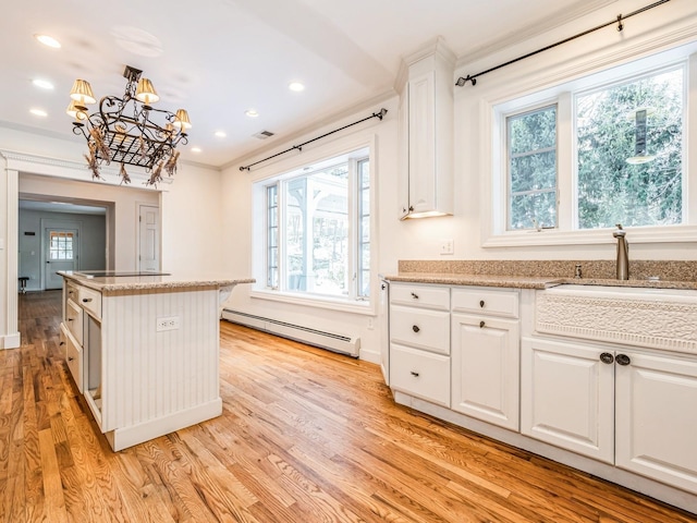 kitchen featuring pendant lighting, light hardwood / wood-style flooring, a baseboard heating unit, white cabinets, and a kitchen island