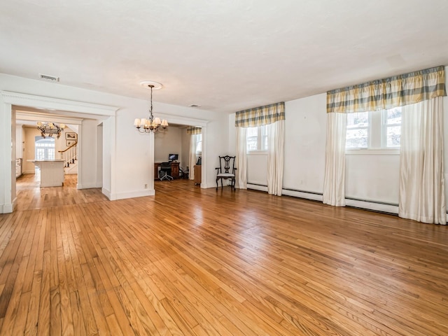 unfurnished living room with a chandelier, light wood-type flooring, and baseboard heating