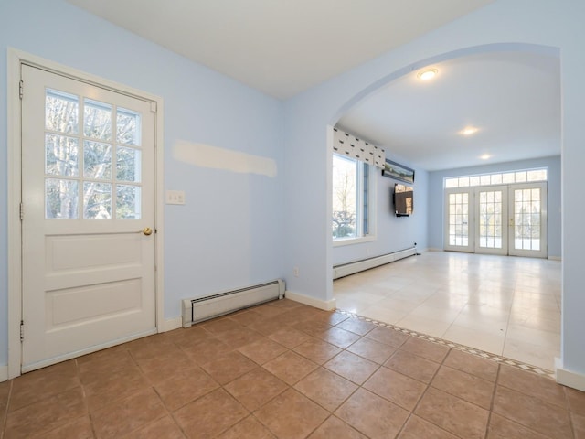 foyer entrance with baseboard heating, light tile patterned flooring, and a wall unit AC