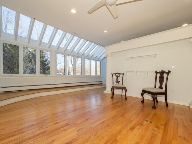 unfurnished room with lofted ceiling, a baseboard heating unit, ceiling fan, and light wood-type flooring