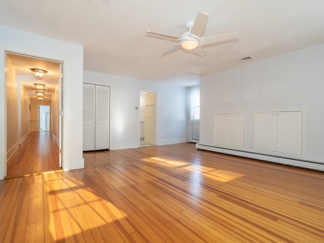 spare room with ceiling fan, a baseboard radiator, and light wood-type flooring