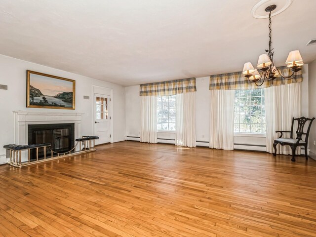 unfurnished living room featuring wood-type flooring, an inviting chandelier, a glass covered fireplace, and visible vents