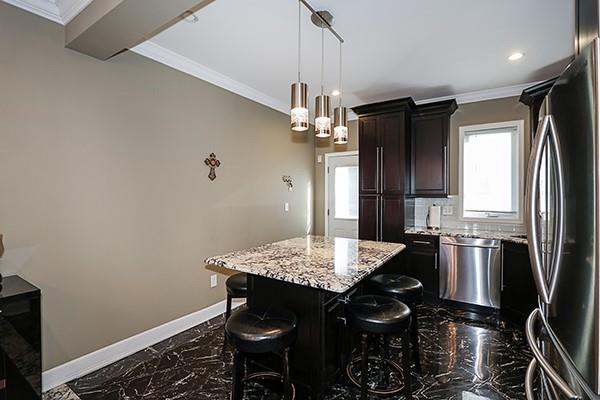 kitchen with a center island, light stone countertops, appliances with stainless steel finishes, a kitchen breakfast bar, and ornamental molding