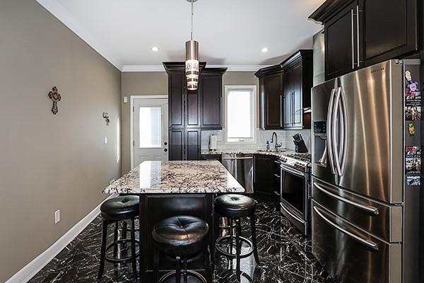 kitchen with light stone countertops, a center island, decorative light fixtures, stainless steel appliances, and a kitchen breakfast bar