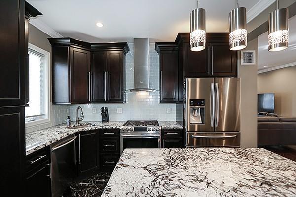 kitchen with hanging light fixtures, appliances with stainless steel finishes, sink, tasteful backsplash, and wall chimney range hood