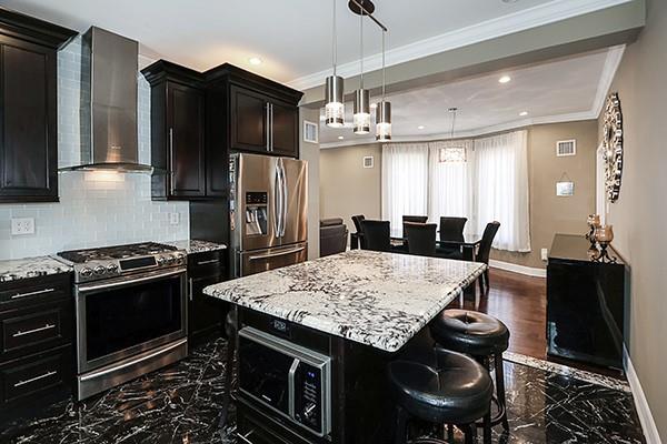 kitchen featuring a kitchen bar, tasteful backsplash, wall chimney range hood, a kitchen island, and stainless steel appliances