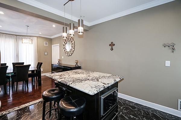 kitchen featuring pendant lighting, a kitchen island, crown molding, a breakfast bar area, and built in microwave