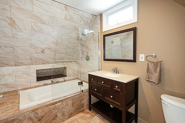 full bathroom featuring tiled shower / bath combo, vanity, and toilet