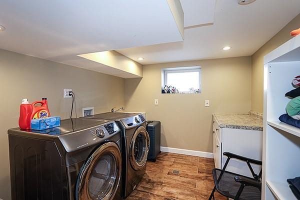 laundry area with wood-type flooring, cabinets, and washer and dryer