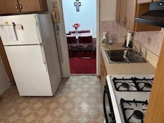 kitchen with white appliances, ventilation hood, sink, and backsplash