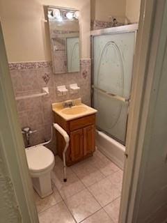 full bathroom featuring tile patterned flooring, vanity, shower / bath combination with glass door, and tile walls