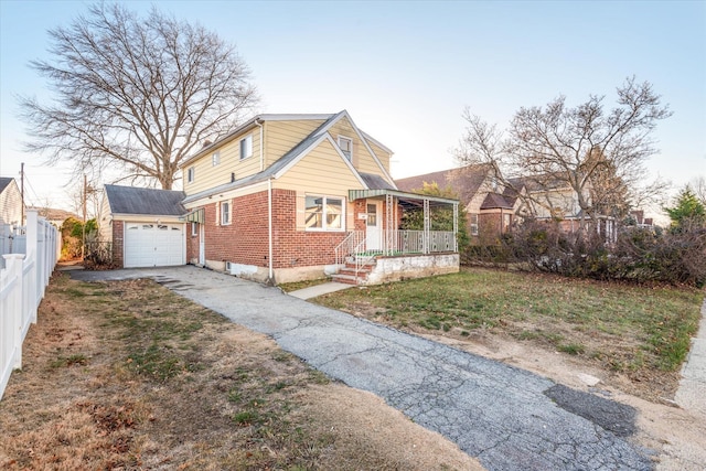 view of front facade featuring a front yard, a porch, a garage, and an outdoor structure