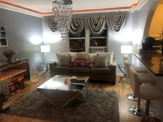 living room featuring hardwood / wood-style flooring, ornamental molding, cooling unit, and a chandelier