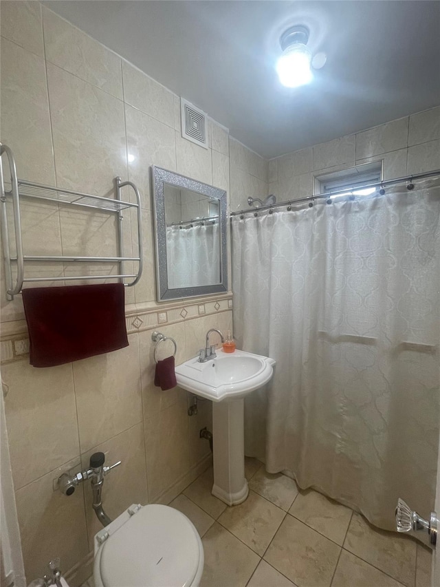 bathroom with tile patterned flooring, tile walls, a shower with shower curtain, and toilet