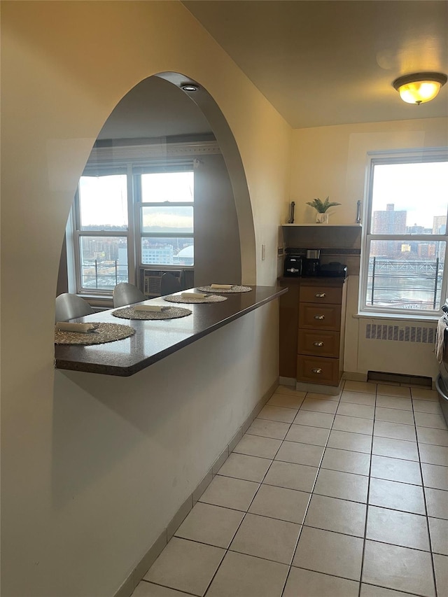 kitchen featuring light tile patterned flooring, radiator heating unit, and kitchen peninsula