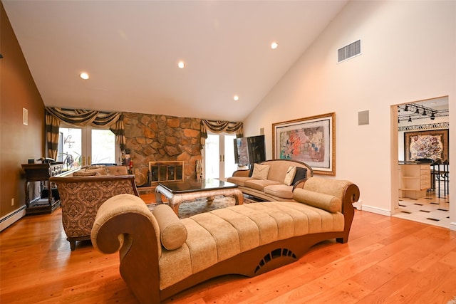 living room featuring a fireplace, light hardwood / wood-style floors, and high vaulted ceiling