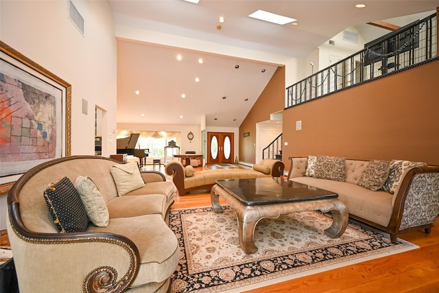 living room with hardwood / wood-style floors, high vaulted ceiling, and a baseboard heating unit