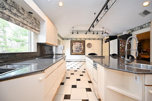 kitchen featuring a center island, hanging light fixtures, dark stone counters, and sink