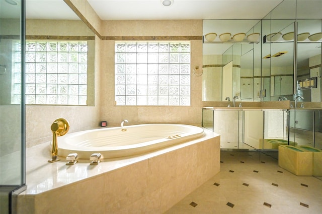 bathroom featuring tile patterned flooring, vanity, and tiled bath