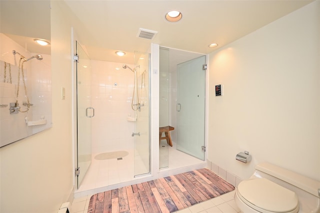 bathroom featuring toilet, tile patterned floors, and a shower with shower door