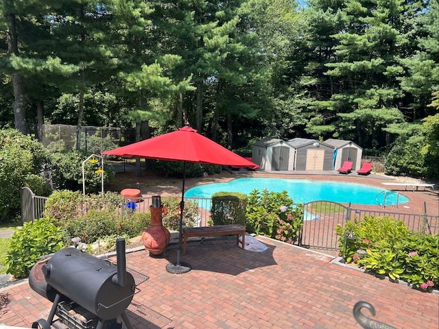 view of swimming pool featuring grilling area, a patio, and a storage shed