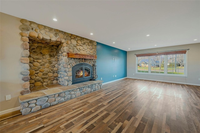 unfurnished living room featuring hardwood / wood-style floors and a stone fireplace