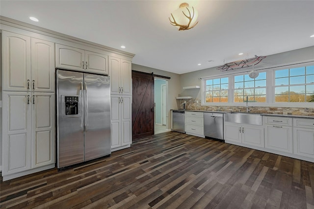 kitchen featuring light stone countertops, white cabinetry, stainless steel appliances, a barn door, and dark hardwood / wood-style floors